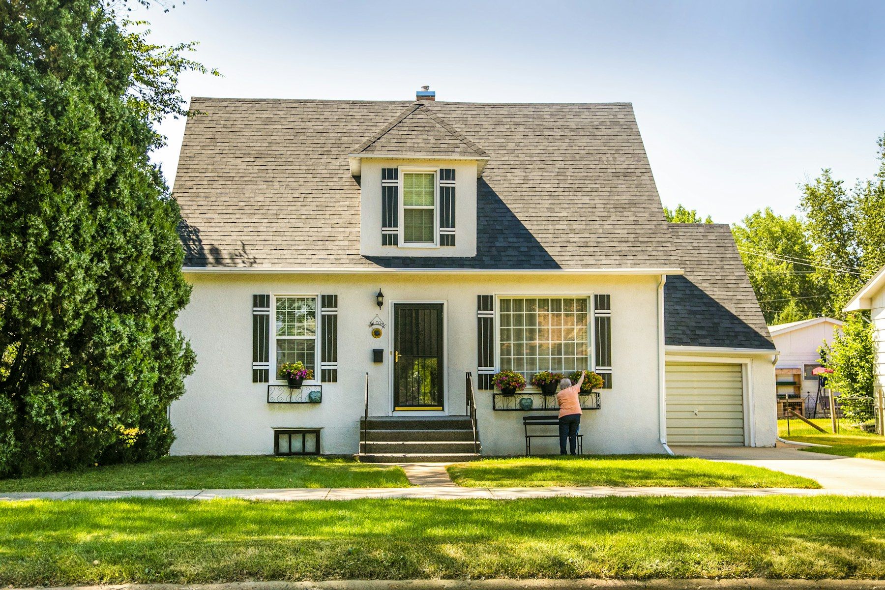 A white house with a green lawn and trees